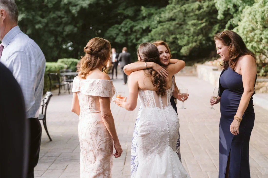 bride hugs guest at cocktail hour