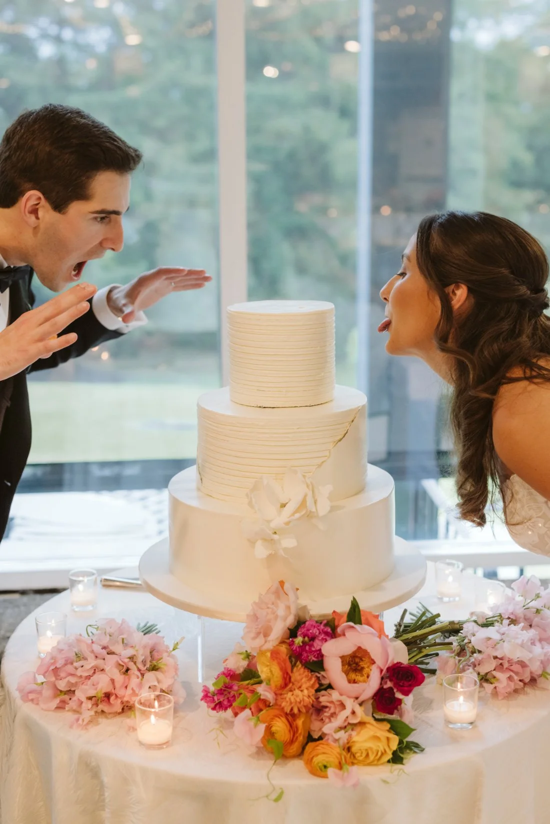 bride and groom playfully interacting with wedding cake 