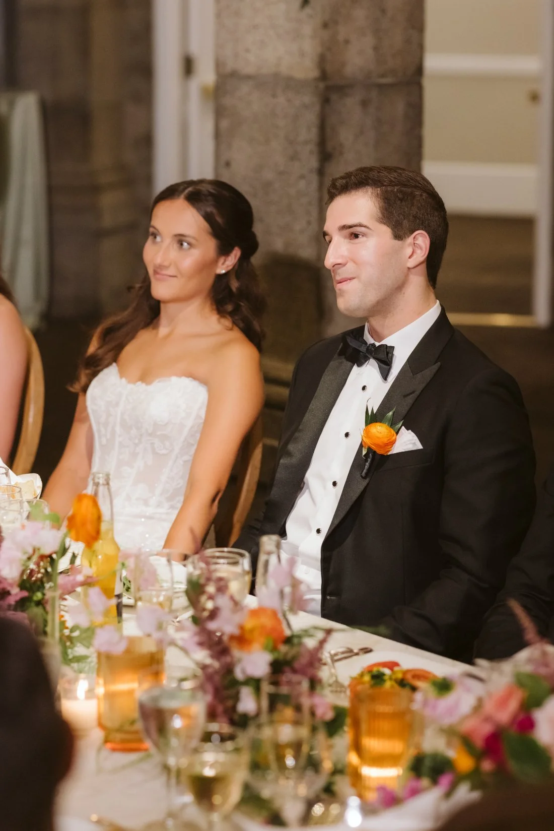 Sydney and Matt enjoying their wedding reception dinner surrounded by colorful flowers and candlelight at Tappan Hill Mansion.