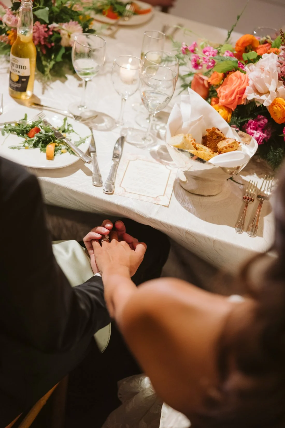 bride and groom holding hands under the table.