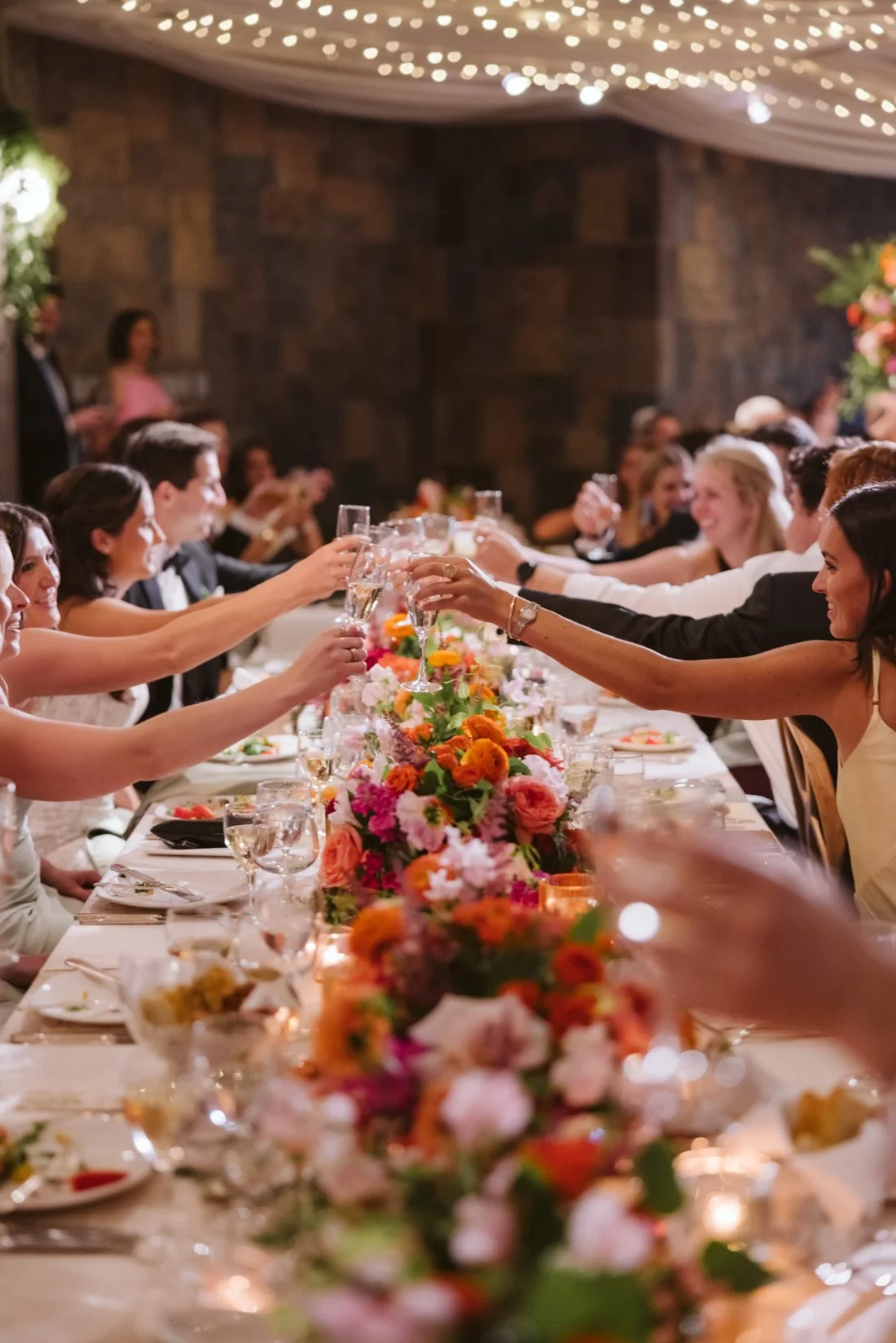 Wedding guests raising champagne glasses during a celebratory toast at a colorful Tappan Hill Mansion wedding reception.