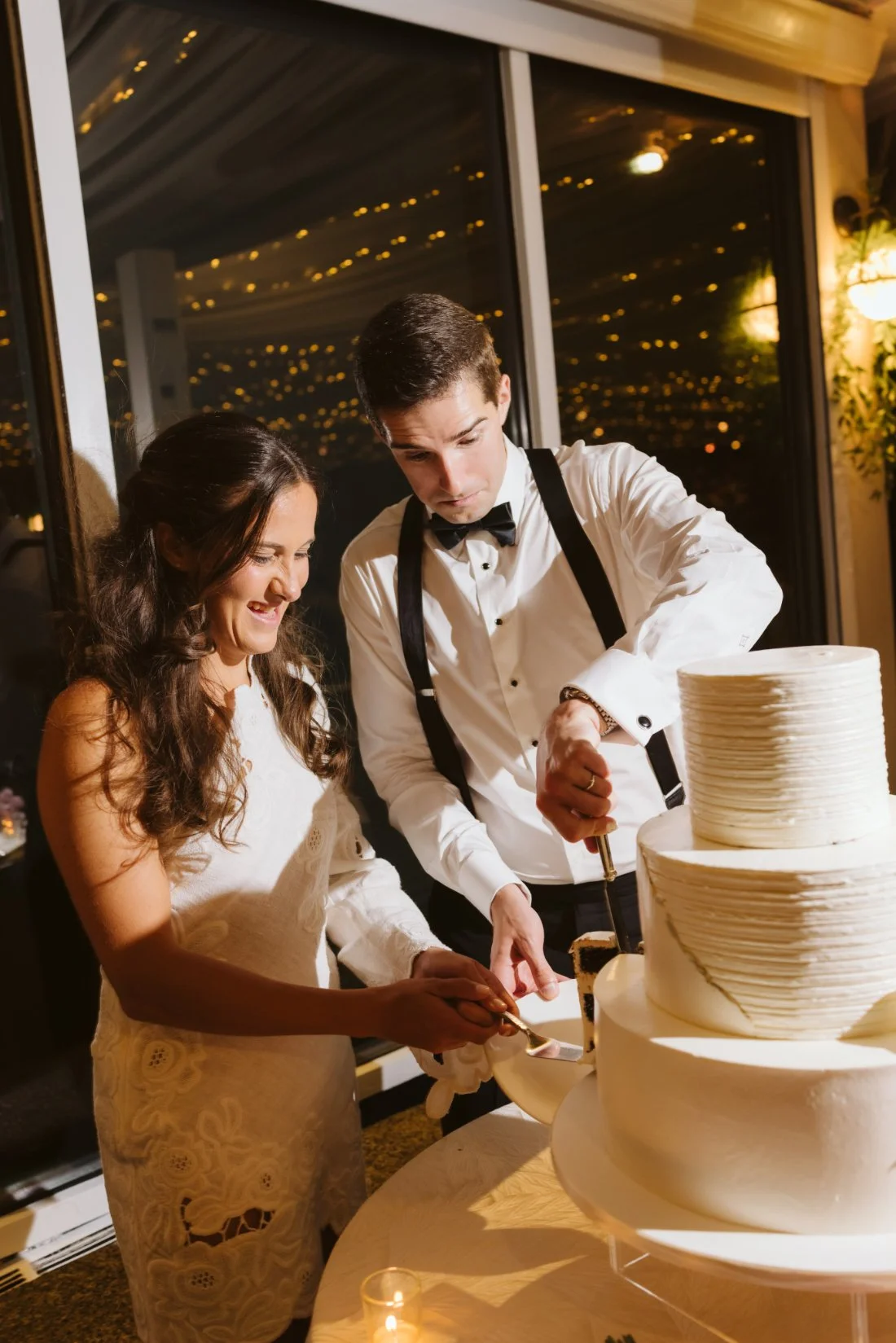 Sydney and Matt cutting their three-tier white wedding cake during their Tappan Hill Mansion wedding reception.
