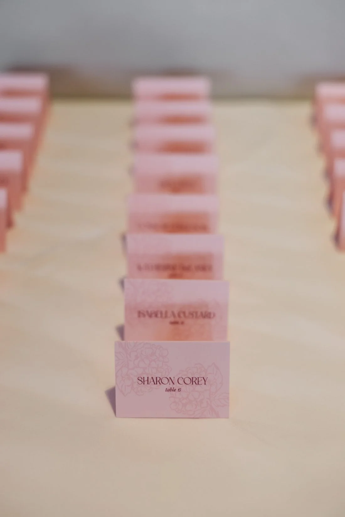 Pink floral escort cards arranged for guests at a rehearsal dinner before a Tappan Hill Mansion wedding.