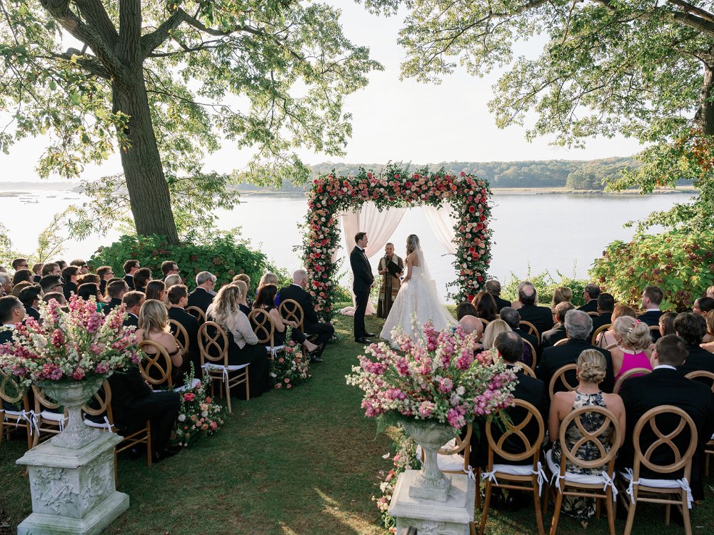 Lessons in business inspired by an elegant waterfront wedding ceremony with a floral arch and guests overlooking the water.