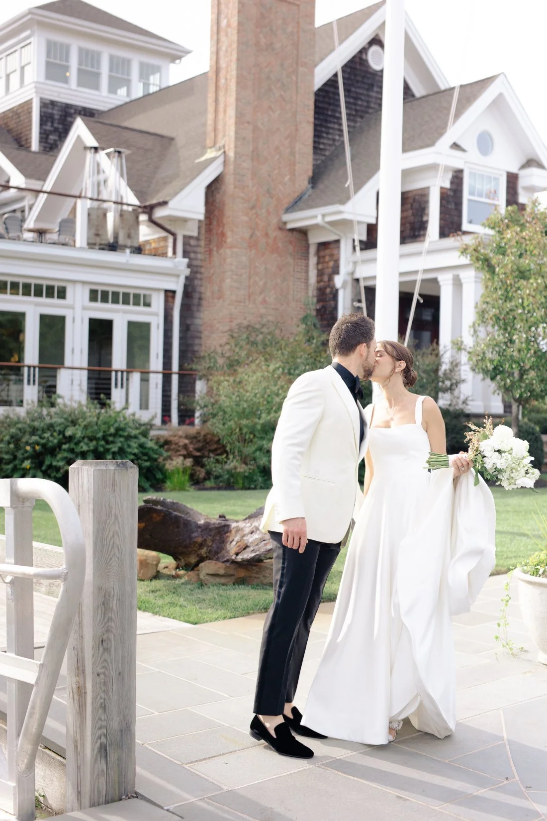 bride and groom kissing in front of the yacht club