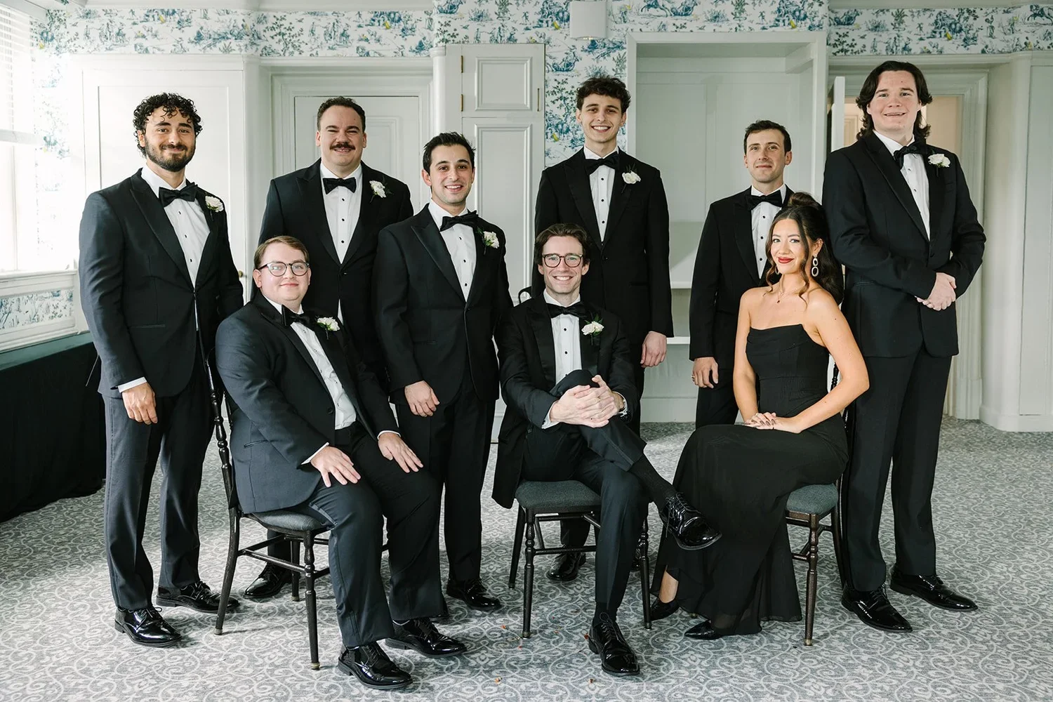 Wedding attendants pose together in formal black attire, showing how bridal party expectations can include a coordinated dress code.