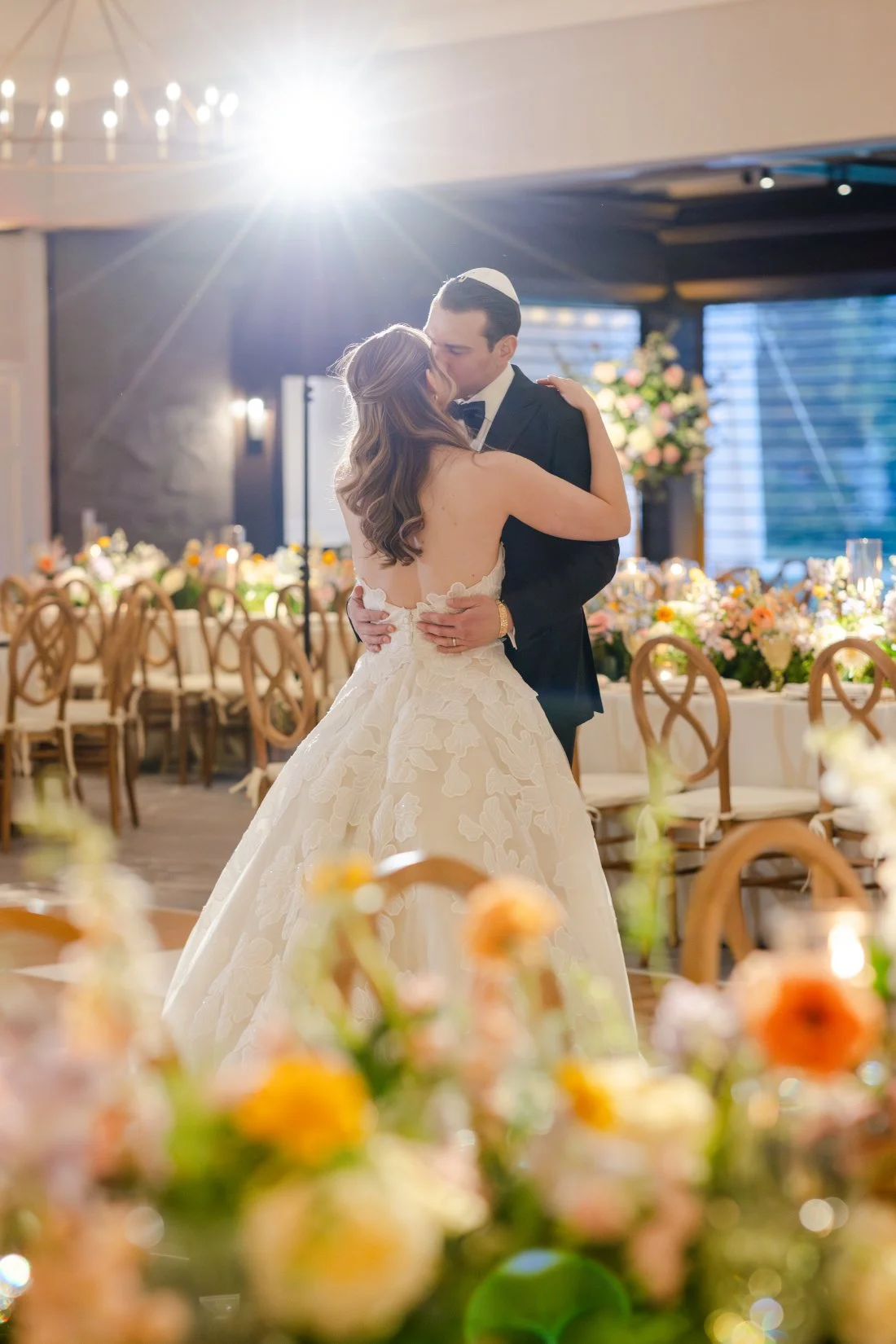 wedding lighting ideas -couple sharing a kiss in their reception space.