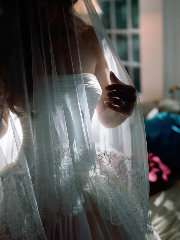 Close-up of bride holding her veil in soft morning light, highlighting elegant bridal details before the ceremony