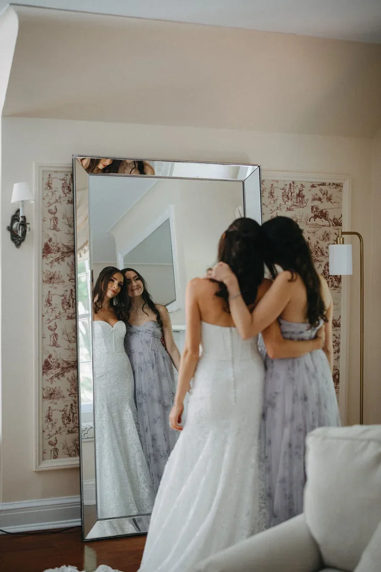 Bride shares a quiet getting-ready moment with a bridesmaid, showing how bridal party expectations can leave room for connection.