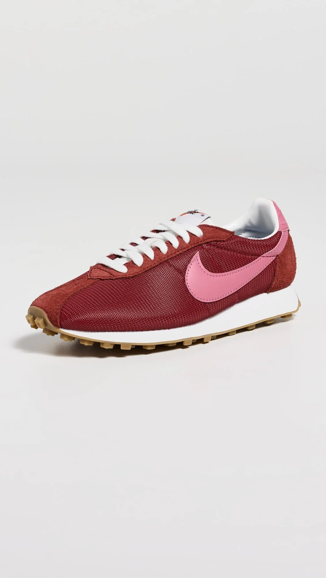 Red athletic sneaker with pink Nike swoosh logo, white laces, and beige sole on a white background.