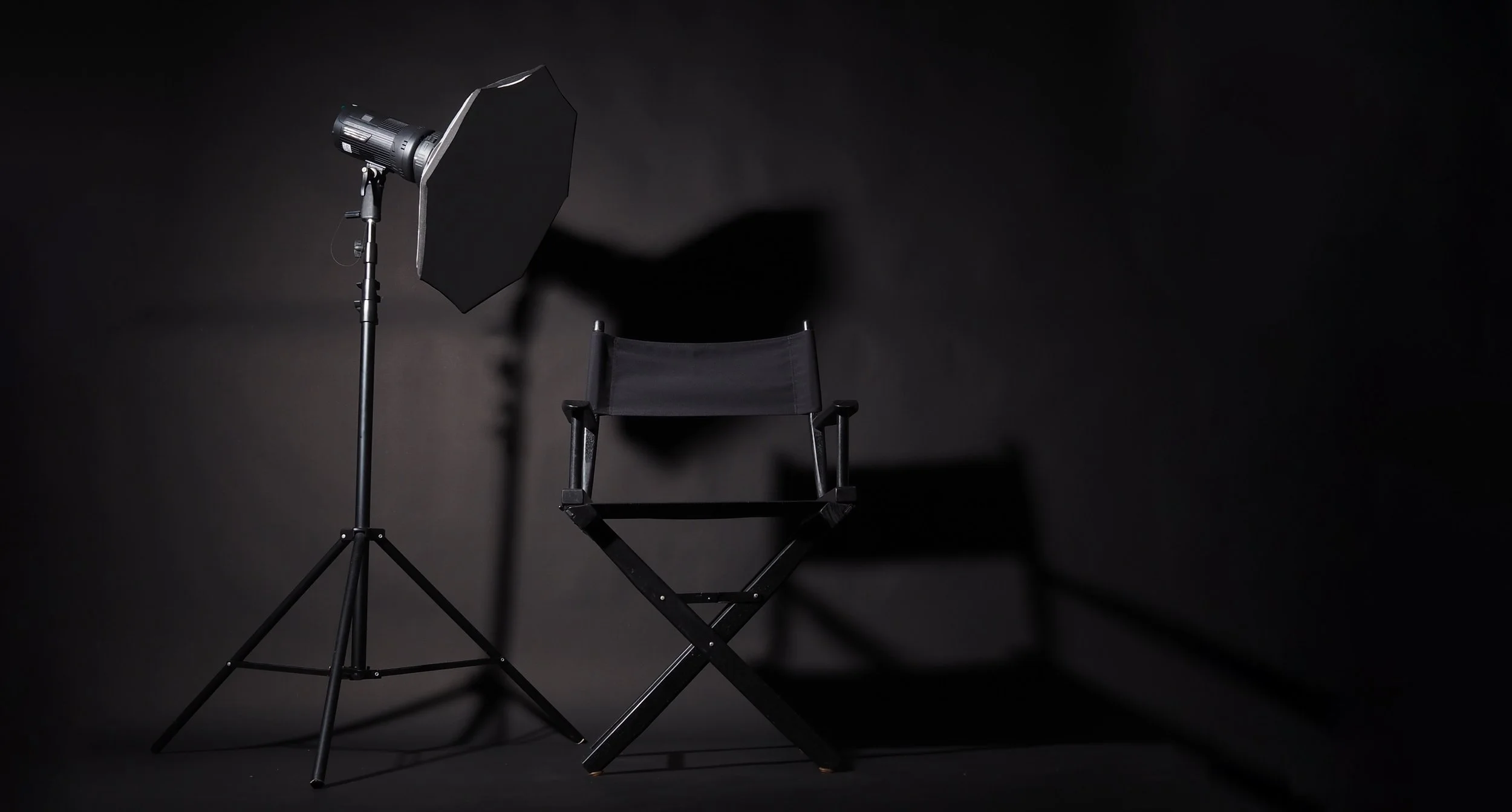 Black_Director_Chair_And_Studio_Light_On_Black_Background_original_2886743.jpg