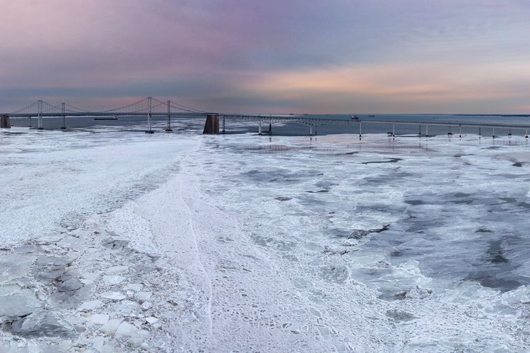 The Chesapeake Bay Bridge beyond a frozen, snow-covered Bay