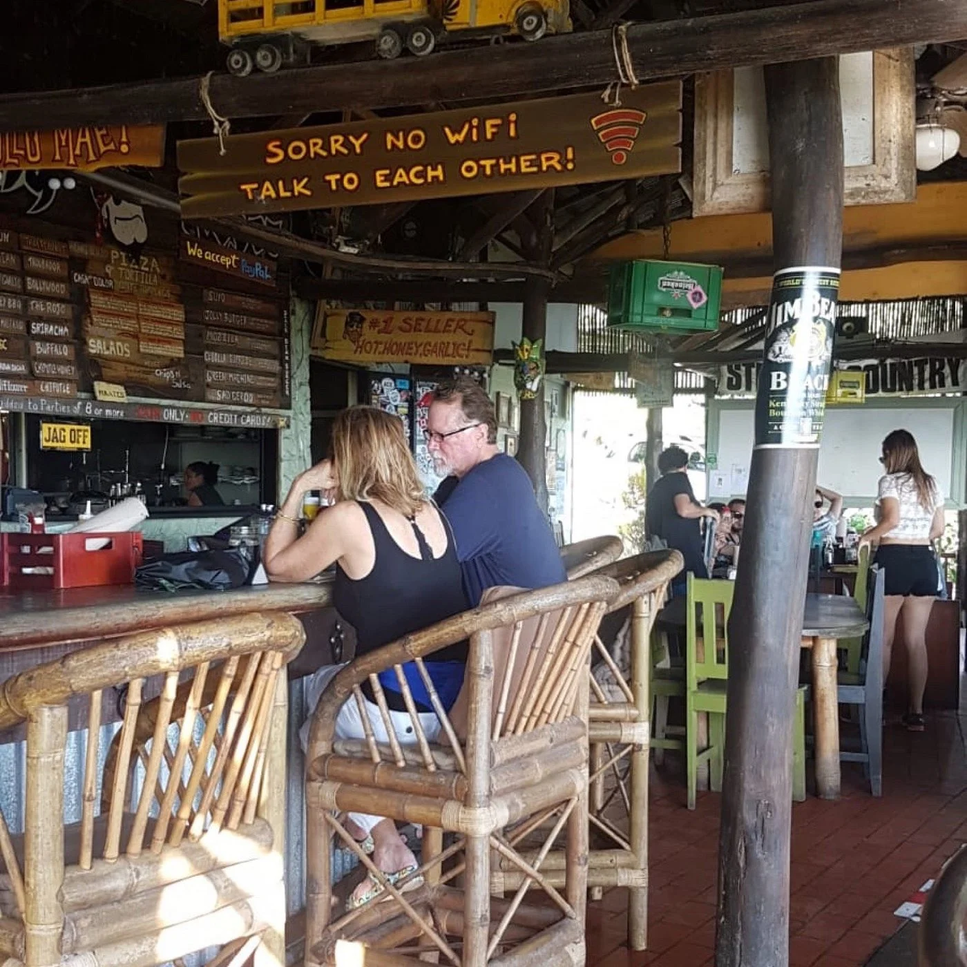 The interior of Tortilla Flats Bar and Restaurant with a rustic decor, bamboo chairs, and a wooden sign reading "Sorry No WiFi Talk to Each Other!"