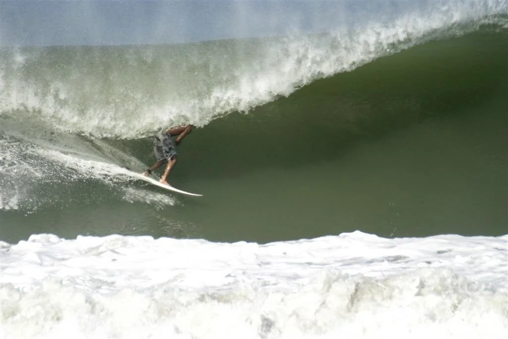 A person surfing a large green wave in the ocean.