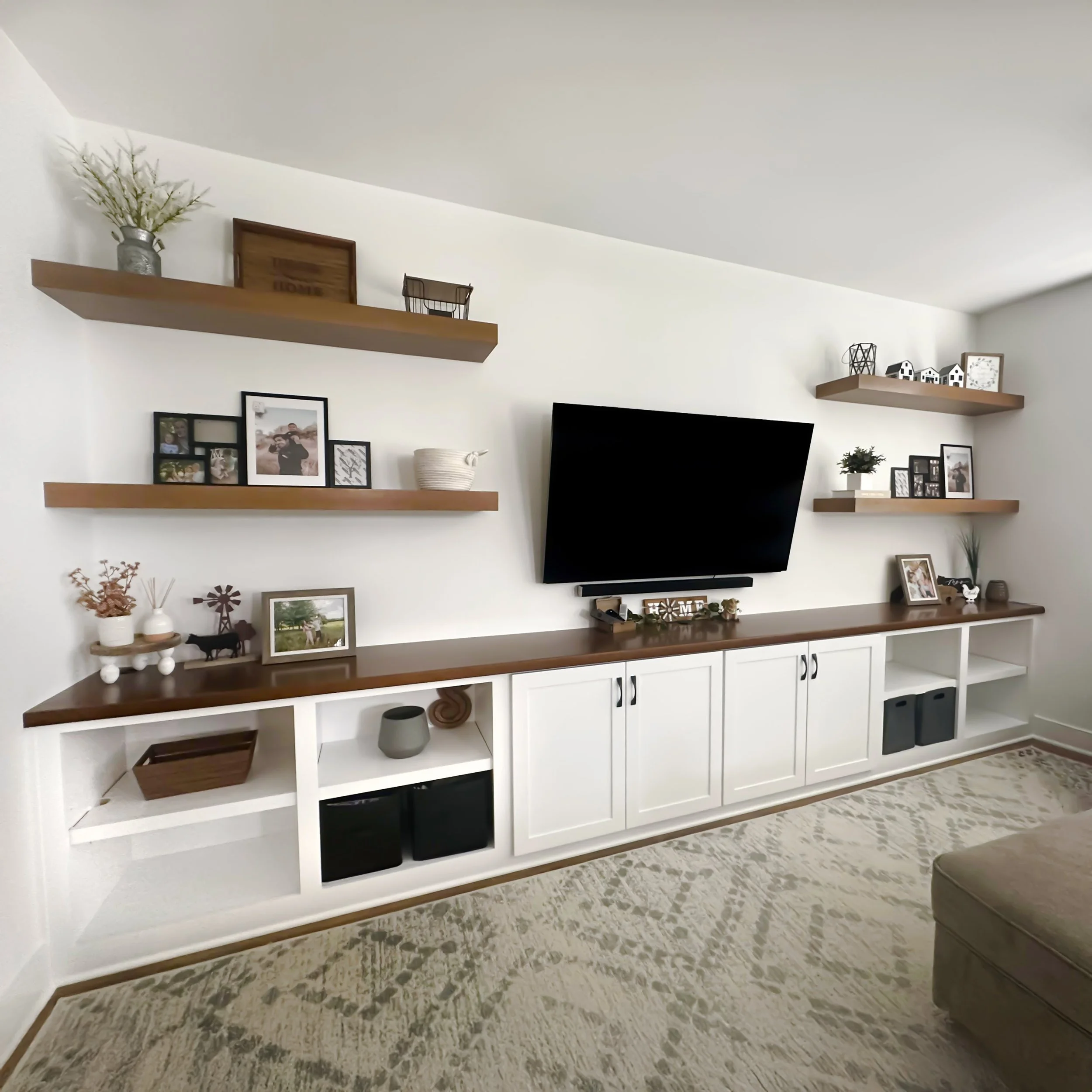 Built-in entertainment center with base cabinets and stained wood floating shelves