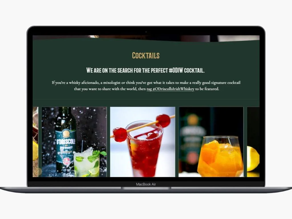 Laptop screen displaying a webpage about cocktails, featuring images of three different cocktails and a bottle of whiskey.