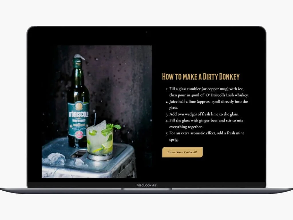 Laptop screen displaying a cocktail recipe titled "How to Make a Dirty Donkey" with step-by-step instructions and a photo of a cocktail in a glass with lime slices, mint, and a bottle of O'Driscoll Irish whiskey beside it.