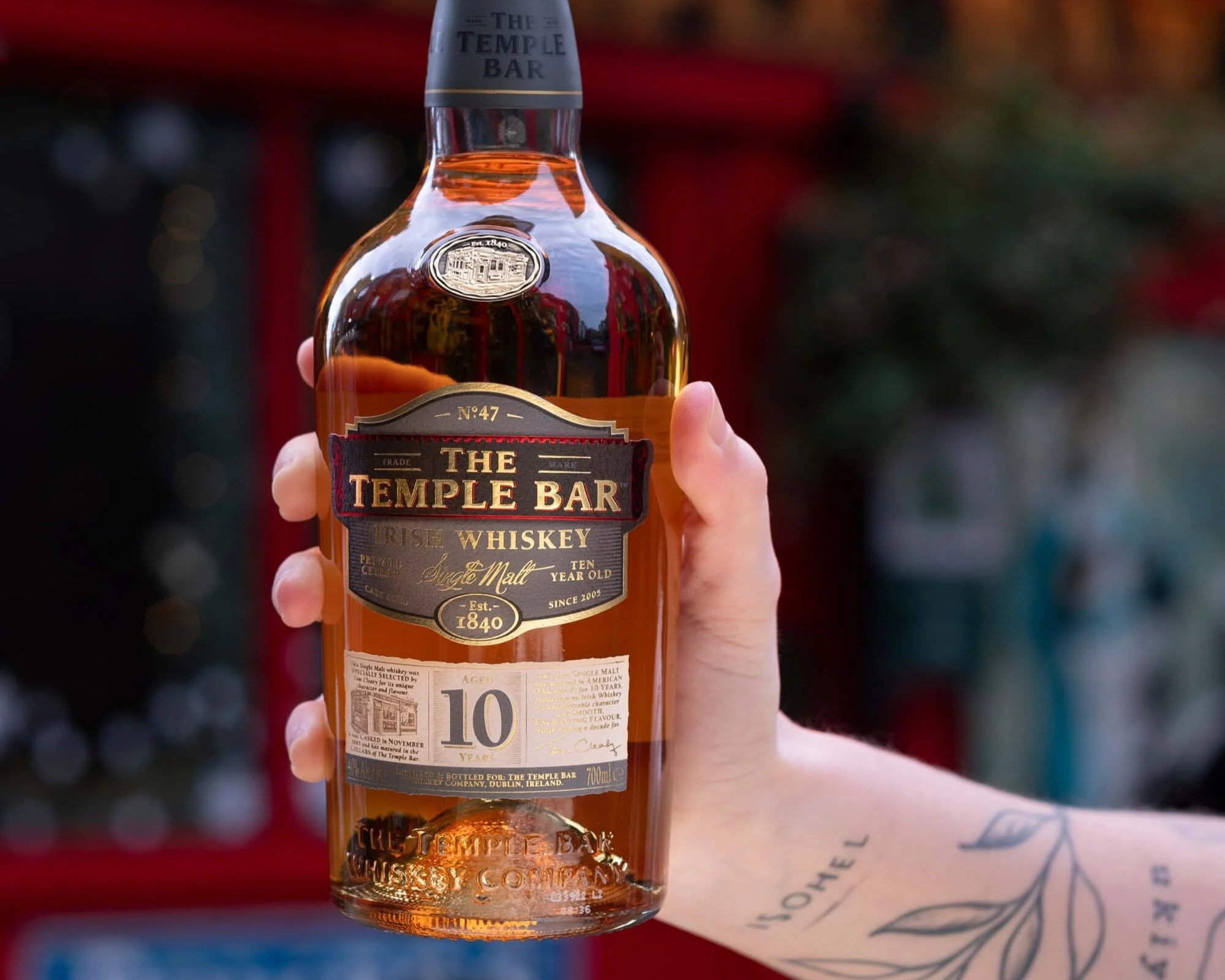 Six bottles of whiskey displayed in front of a window with a classical sculpture of a head behind it. The bottles are from The Temple Bar Irish Whiskey collection, aged 10, 12, 15, 18, and 21 years, with different label designs and colors.