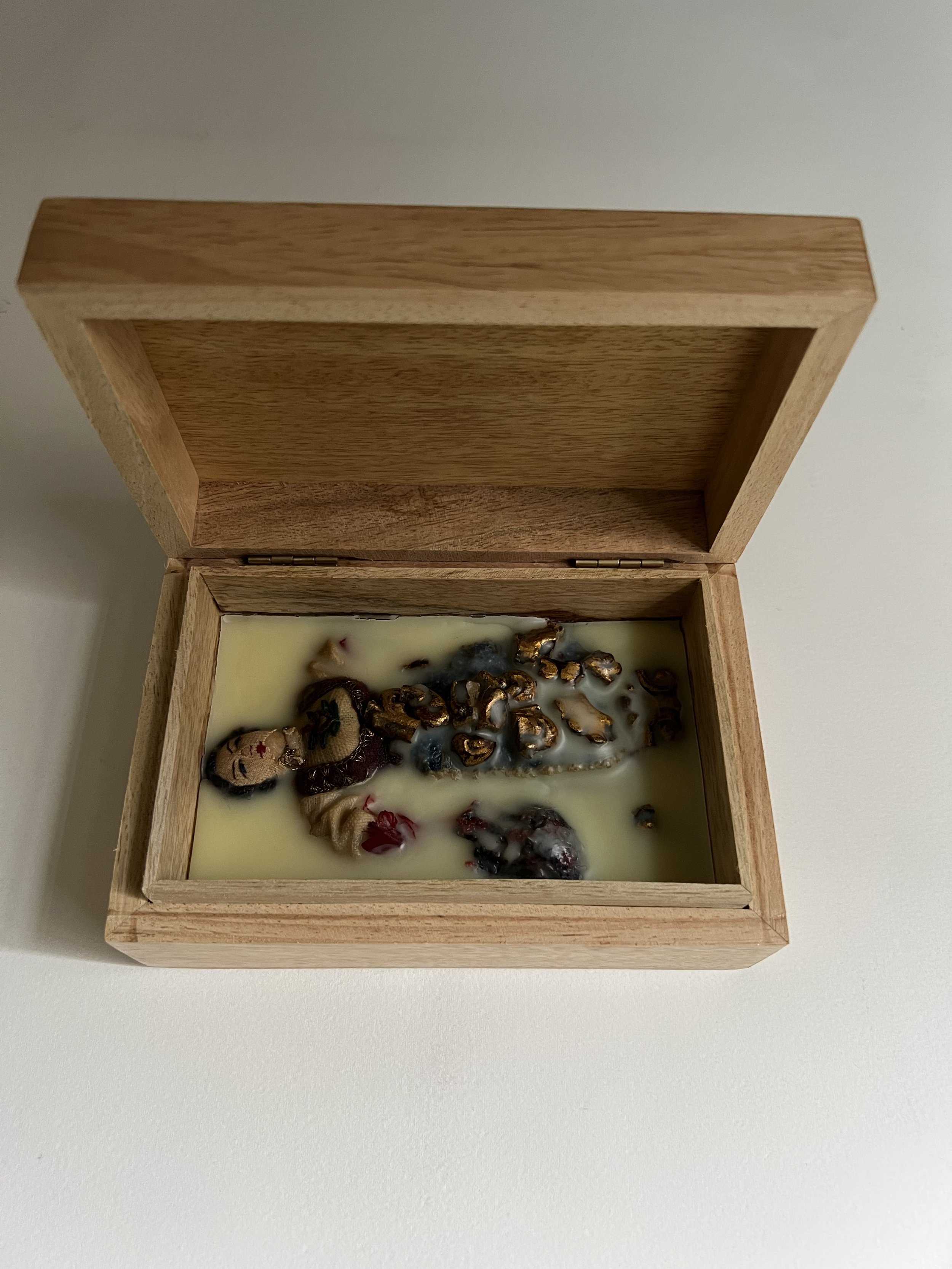   Dwindling Tribe , 2022  Folkloric doll encased in wax and wood  4 x 6 inches   $350.   A folkloric doll embedded in melted wax and displayed in a hand-carved wooden box with a lid.&nbsp;  
