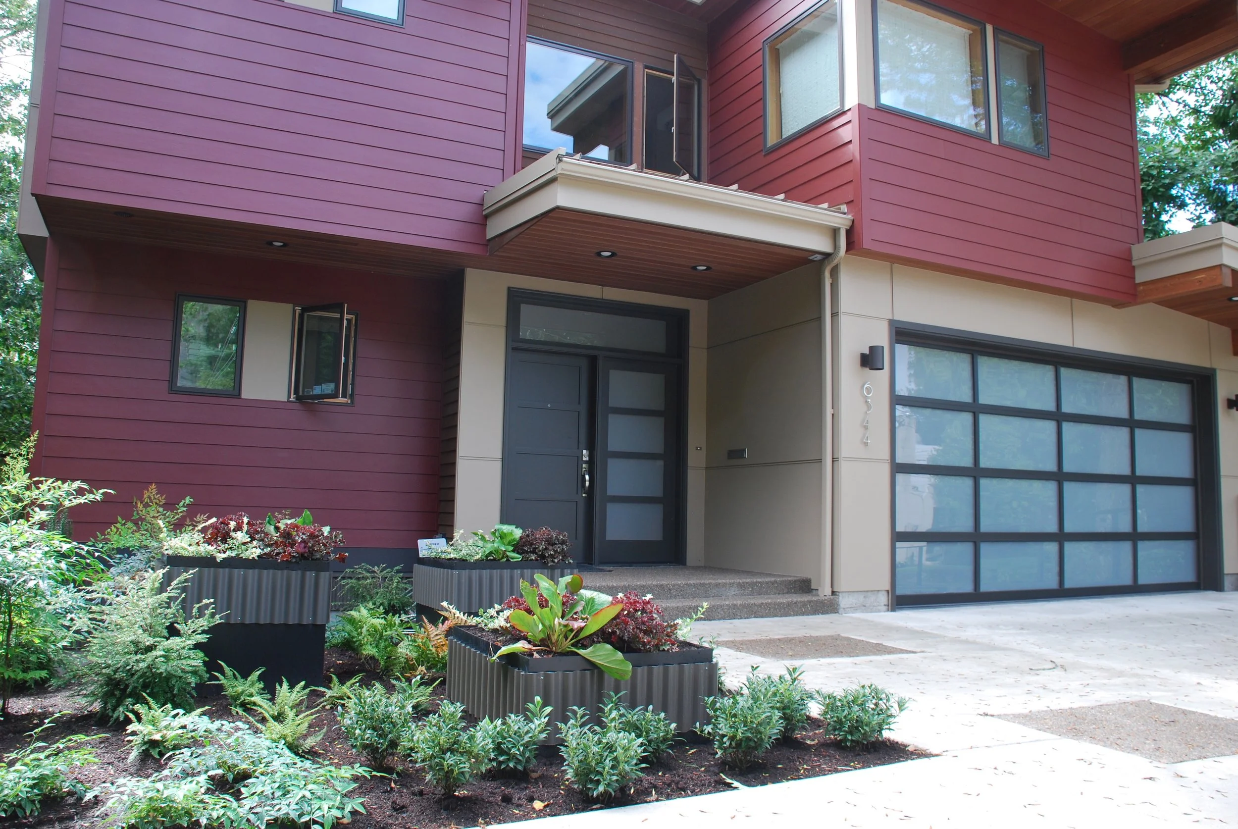 New modern house. Planters match the siding that wraps around the bottom of the house. Plants are drought tolerant. 