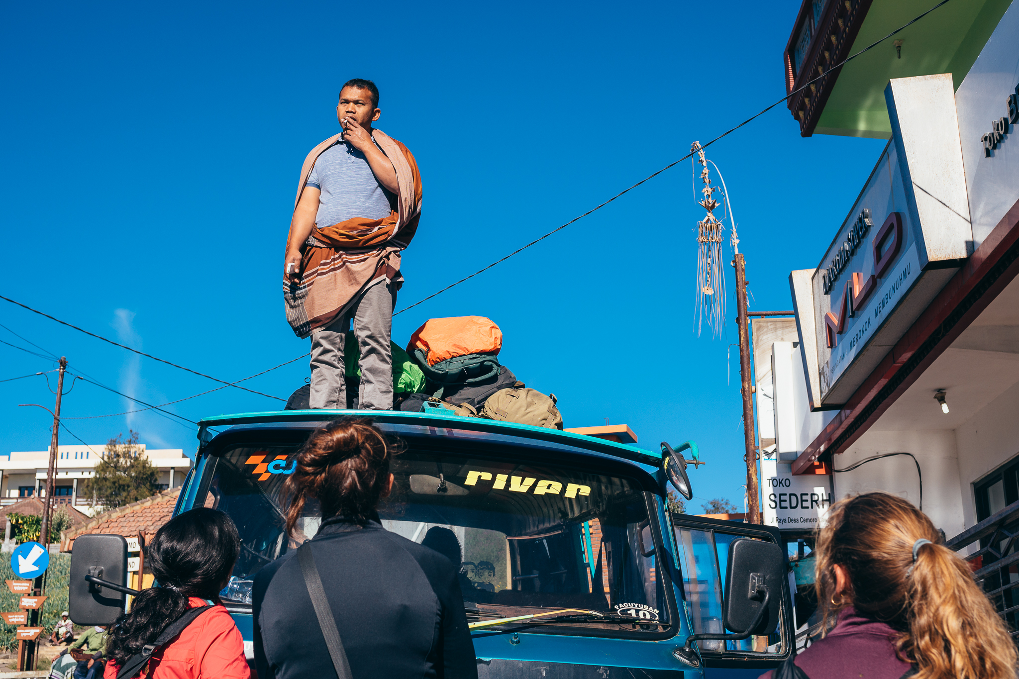 Mini-bus driver accommodating our bags and waiting for an extra passenger at Mount Bromo. ( N ot the scam artist. )