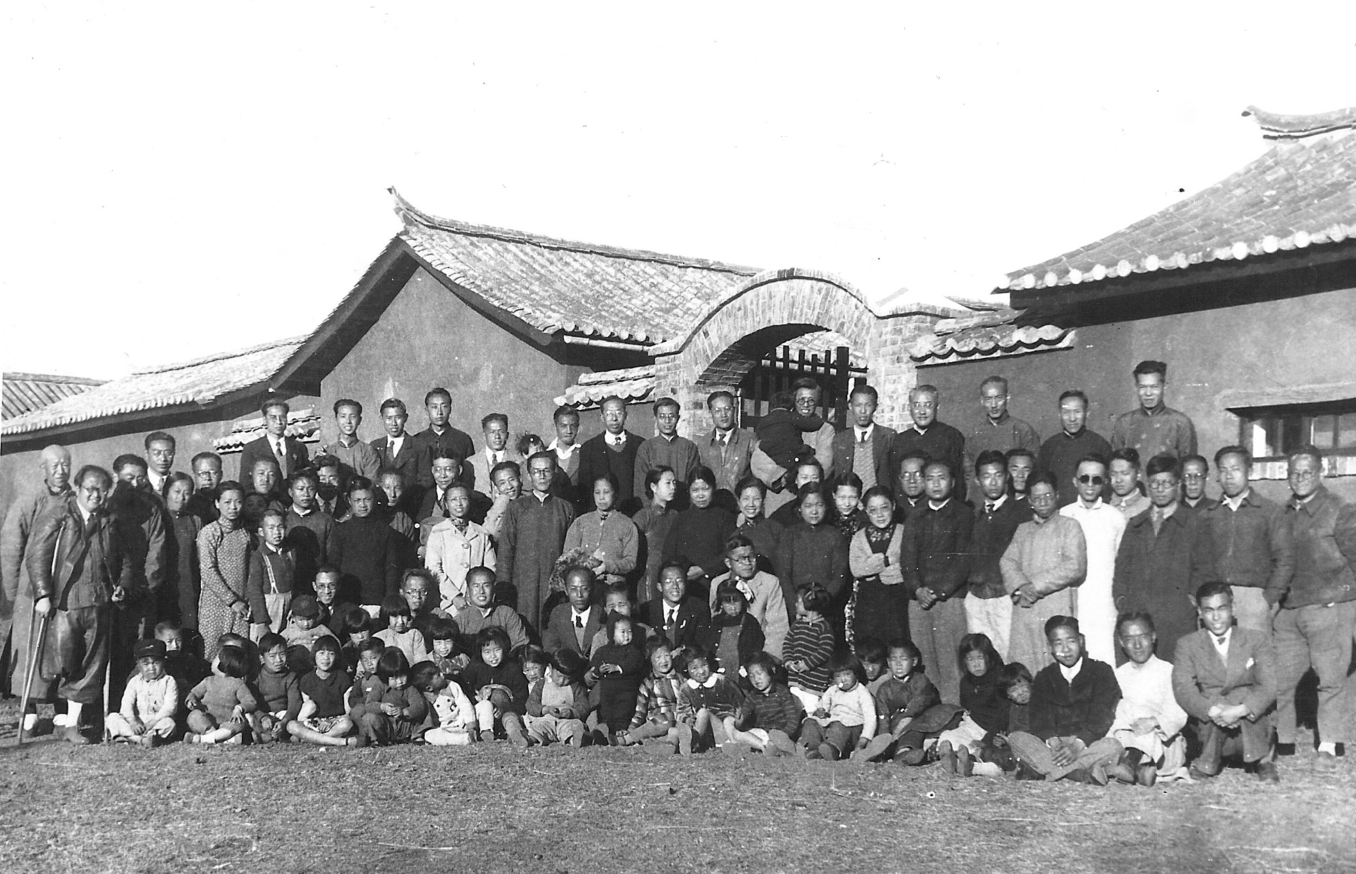 Group photo of faculty and family of National Southwest Associated University (Xinan Lianda), 1940. CK Jen is at the center front row, kneeling down, with his wife, Paocheng Tao, on his right side, her face partly obscured by a standing May, their first-born daughter. Image courtesy George Koo.