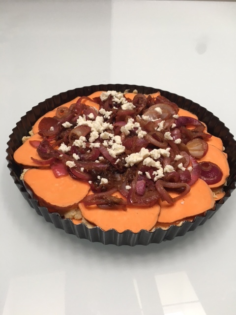 Add your caramelized onions to the center of tart, and sprinkle with a bit of feta for decoration before baking.