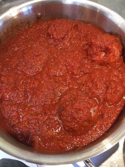 The freshly rolled raw meatballs are placed into the marinara sauce to slow cook to tender perfection.