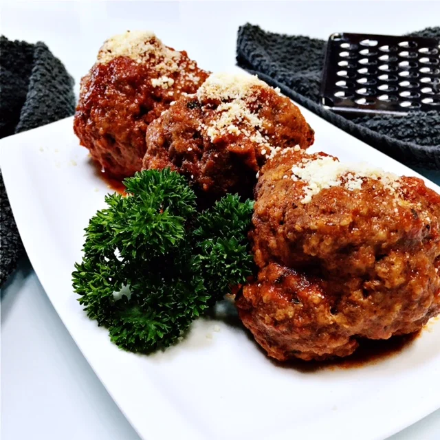 Meatballs in marinara sauce, topped with parmesan cheese and ready to be enjoyed!