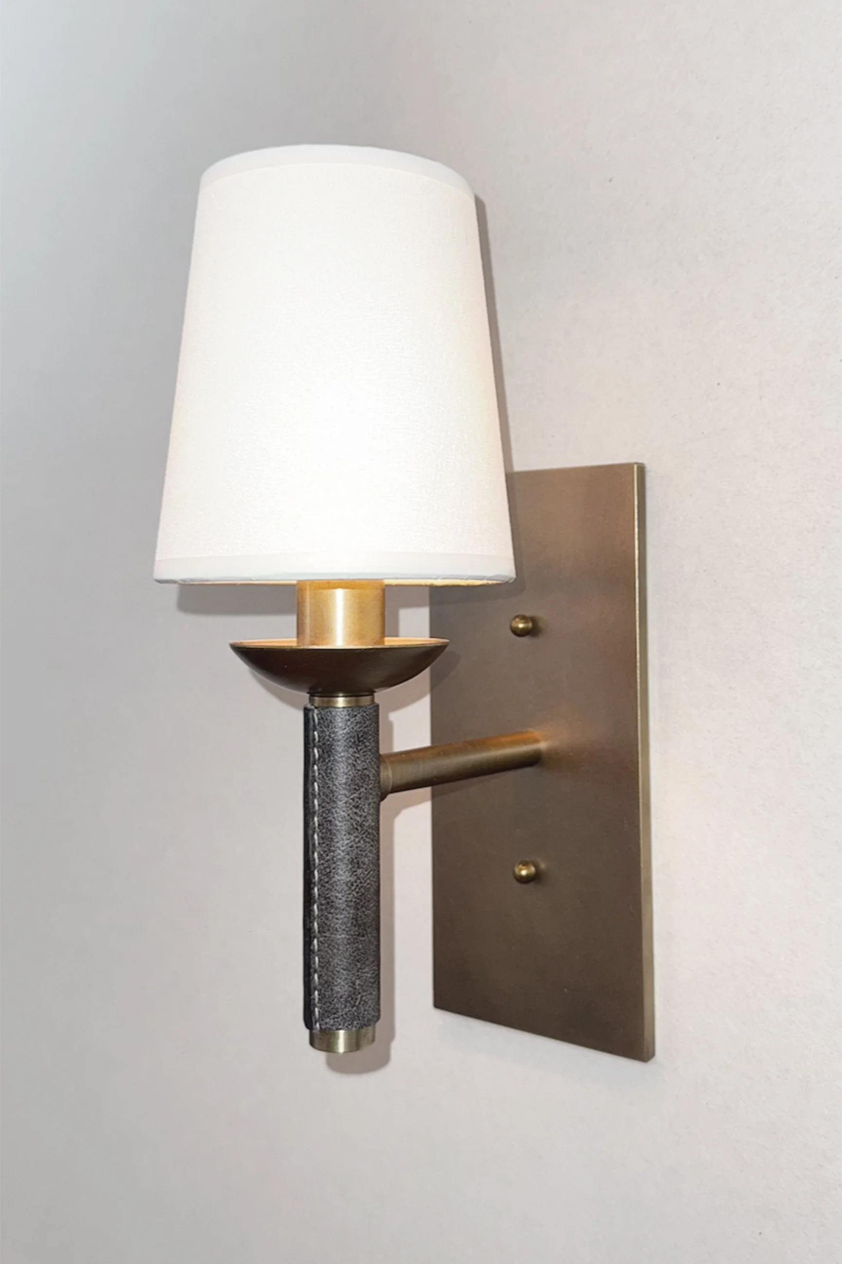 antique brass wall sconce with leather detail and white linen shade