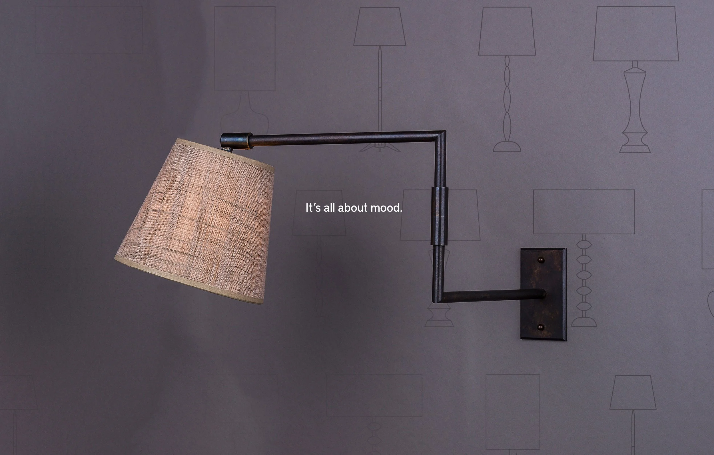 Wall-mounted lamp with beige lampshade, black metal arm, and the text "It's all about mood."