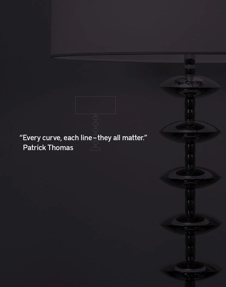 A dark-colored lamp with a stack of round, disc-shaped elements along its stand, and a quote by Patrick Thomas stating, "Every curve, each line - they all matter."