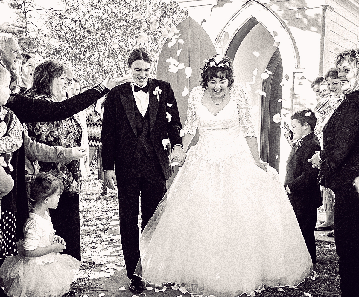 Wedding couple leaving the church while petals are being tossed.jpg