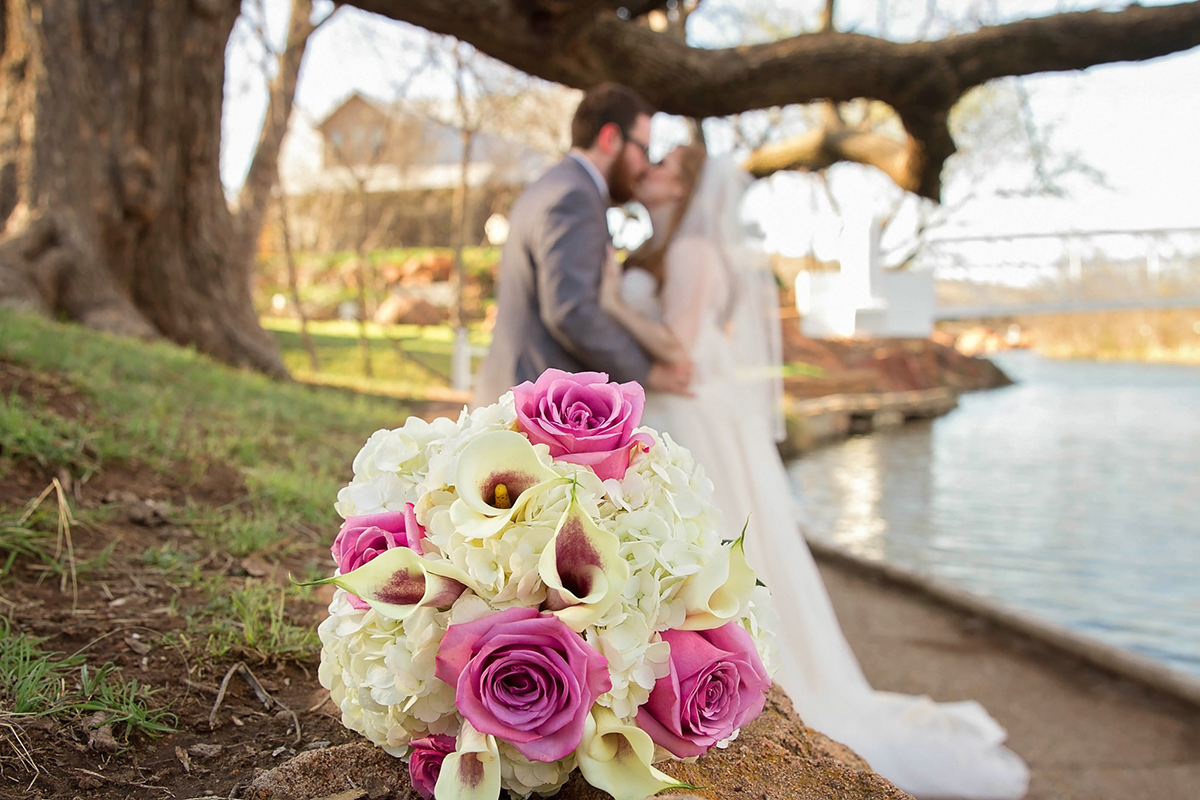 Bridal Bouquet with Bride and Groom kissing in background.jpg