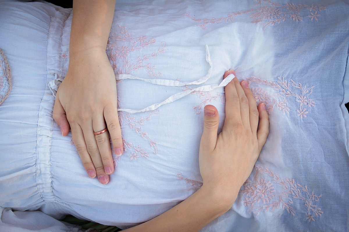 Mom holding baby bump in white lace shirt.jpg