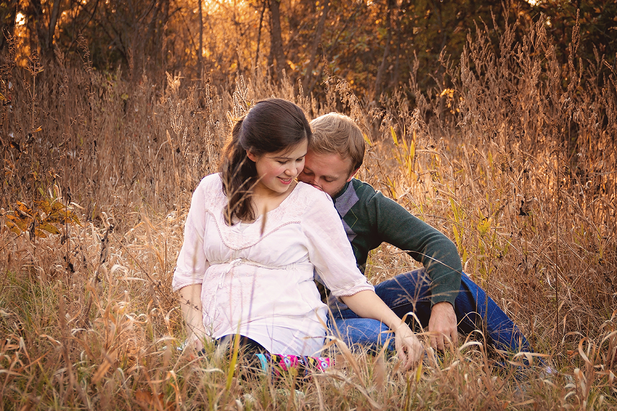 Expectant Mother and father sitting in a overgrown field.jpg