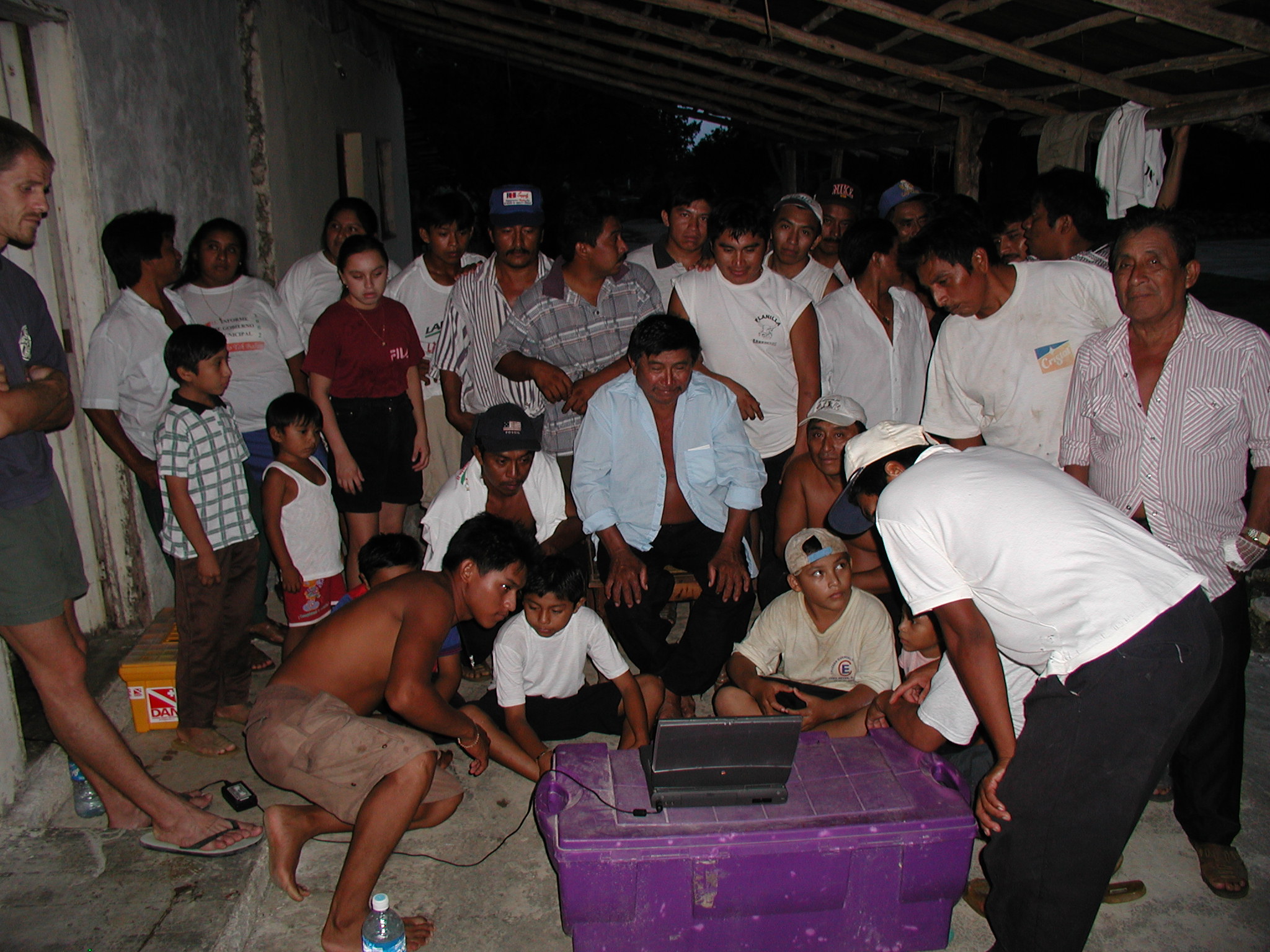 Locals gather around my laptop to see photos of what is in their cenote. In this case a lot of water pails.