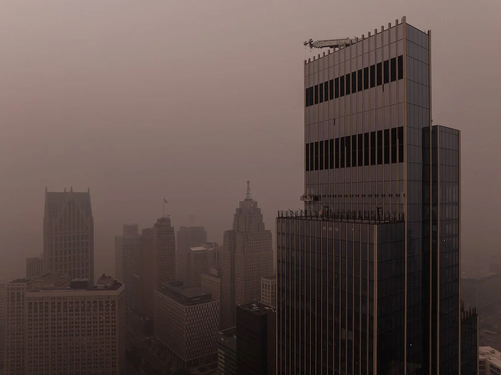 Aerial view of downtown Detroit architecture captured by drone through hazy skies caused by regional wildfire smoke.