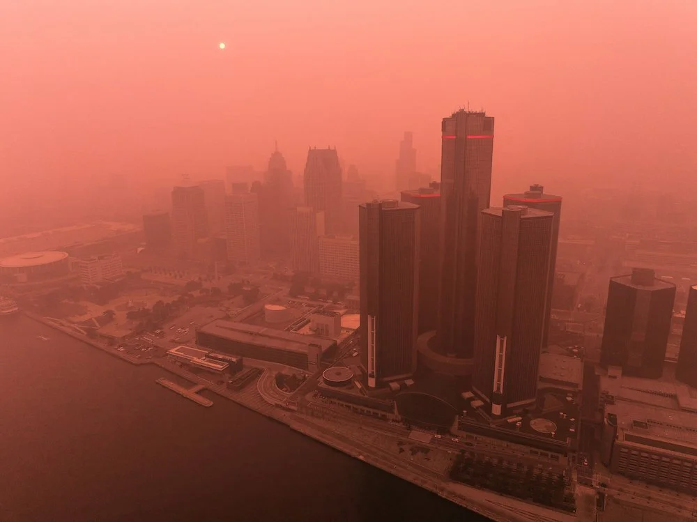 Aerial photograph of downtown Detroit buildings and streets photographed through hazy atmospheric conditions.