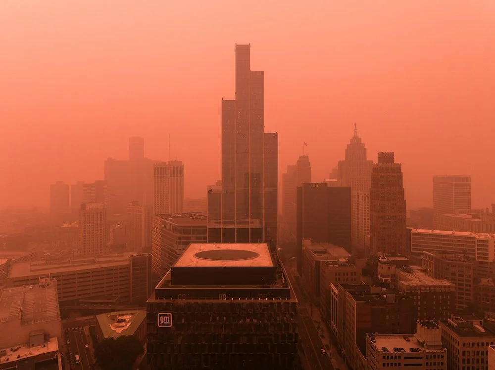 Architectural aerial photograph capturing downtown Detroit beneath smoke-filled summer skies.