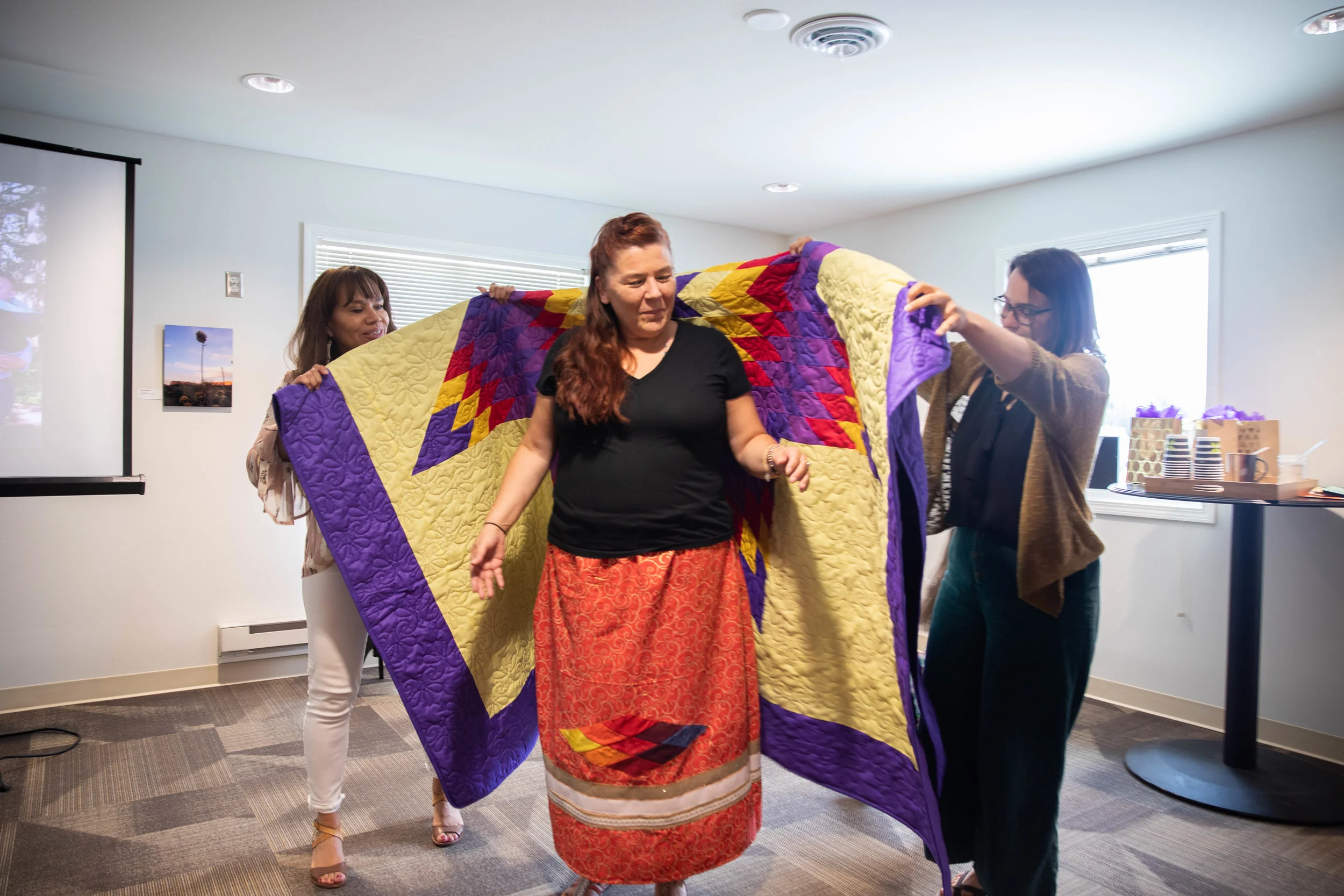 FPF President, Lori Pourier (Oglala Lakota) and FPF Fellowship Program Manager, Amber Hoy, wrap Melissa in a star quilt. Photo by Roxanne Best (Confederated Tribes of the Colville Reservation).