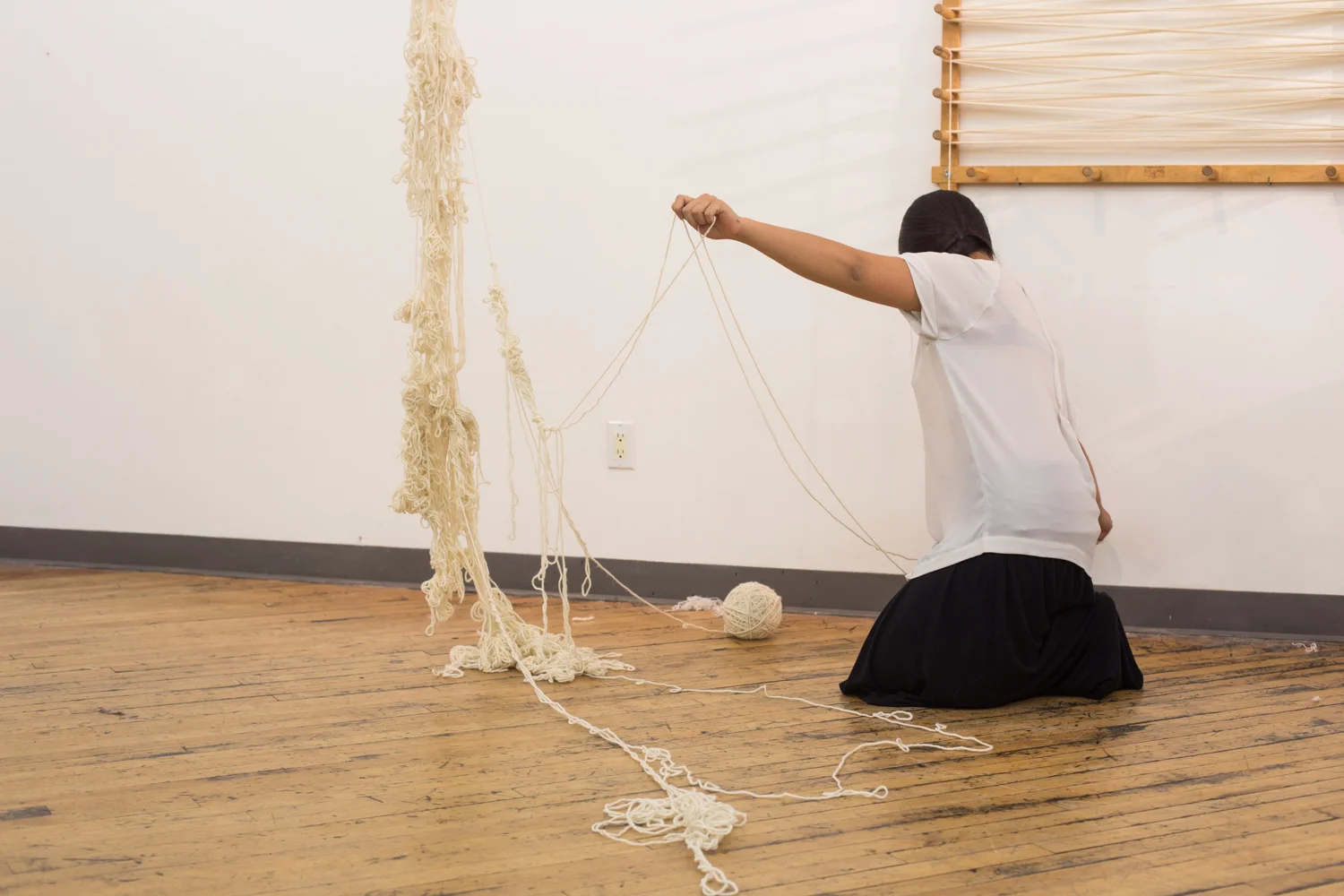 The artist stretches two strands of yarn to create a loop. The ball of untangled yarn is slightly bigger than 3.5 inches in diameter.
