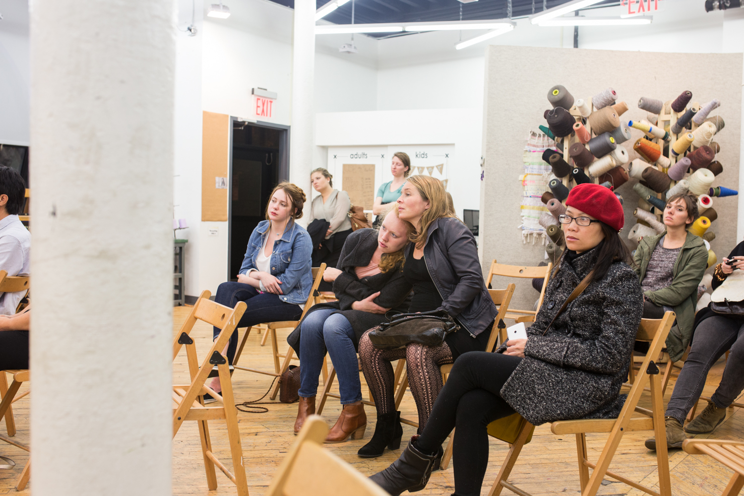 A different group of the audience watches the performance. Two women are leaning onto each other as they hold hands.