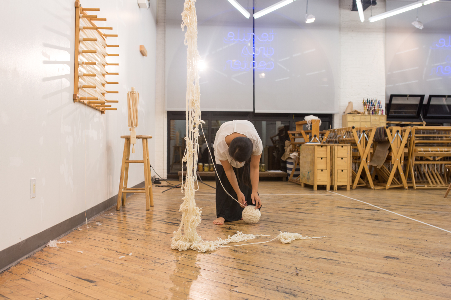 The artist is placing the ball of untangled yarn onto the floor. It’s now at 6 inches in diameter.
