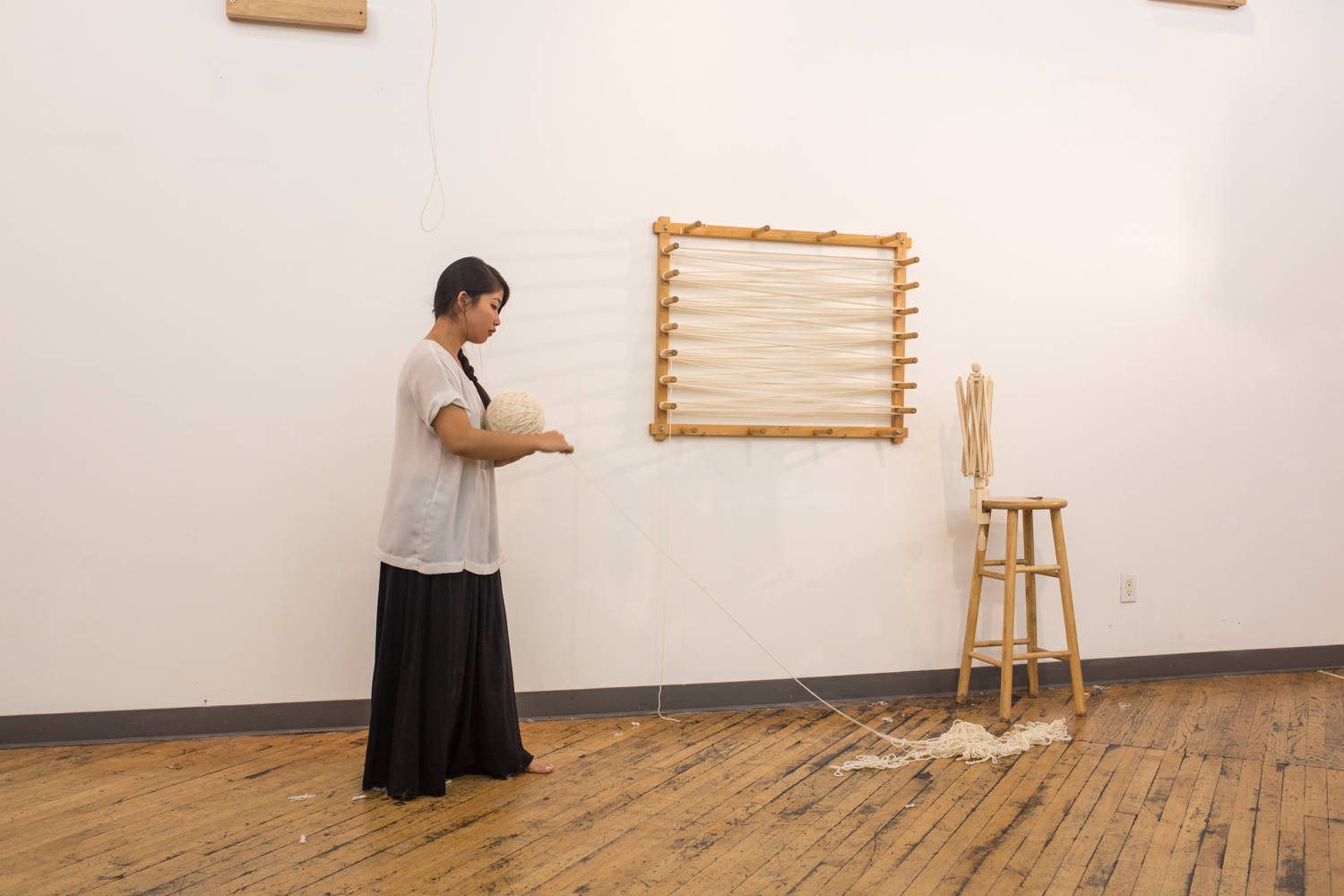 The artist wraps the untangled yarn onto the ball in her hand. Only a small amount of knotted yarn is left.