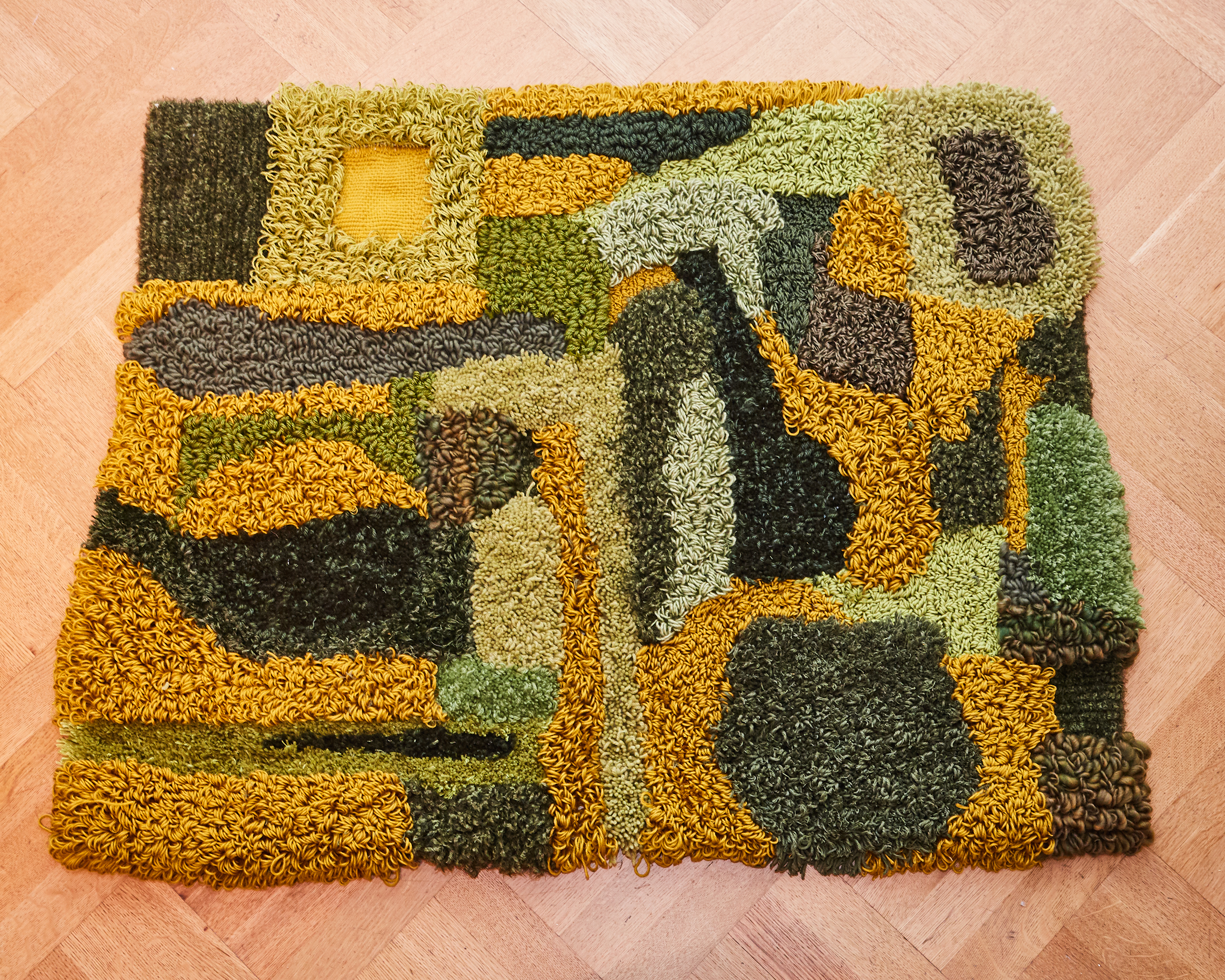 The rug on the floor. The colors are intensified due to the high light exposure. There are many different texture made from different types of yarns, tufting heights, and loop structures.