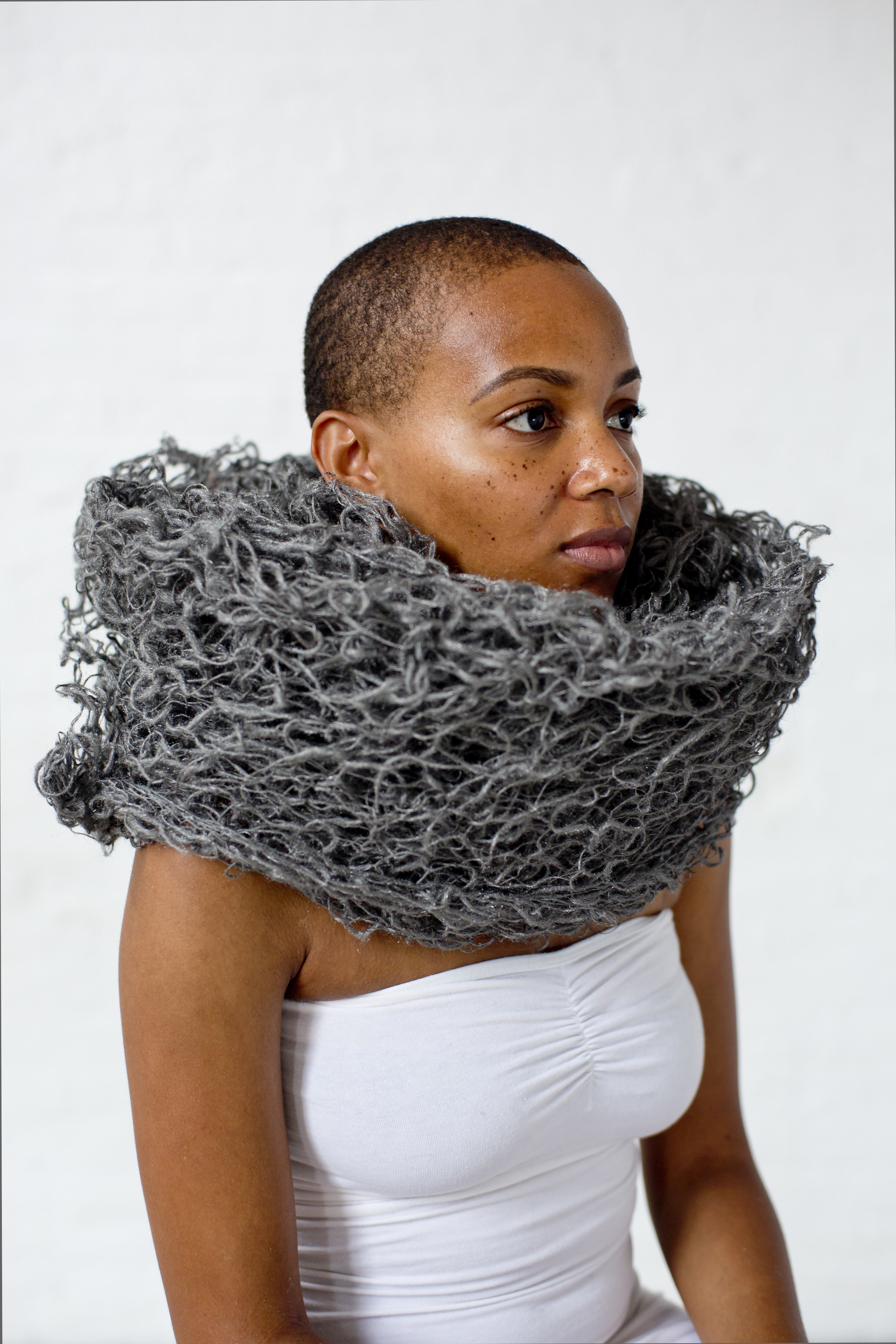 Shaneka Whittick wearing the spun steel wool like a scarf around her neck. The steel wool is knitted together and resembles the roll of un-spun steel wool that can be found at hardware stores.
