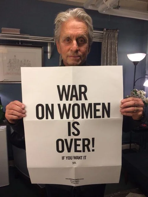 Actor Michael Douglas holding the "War on Women is Over! If You Want It" poster