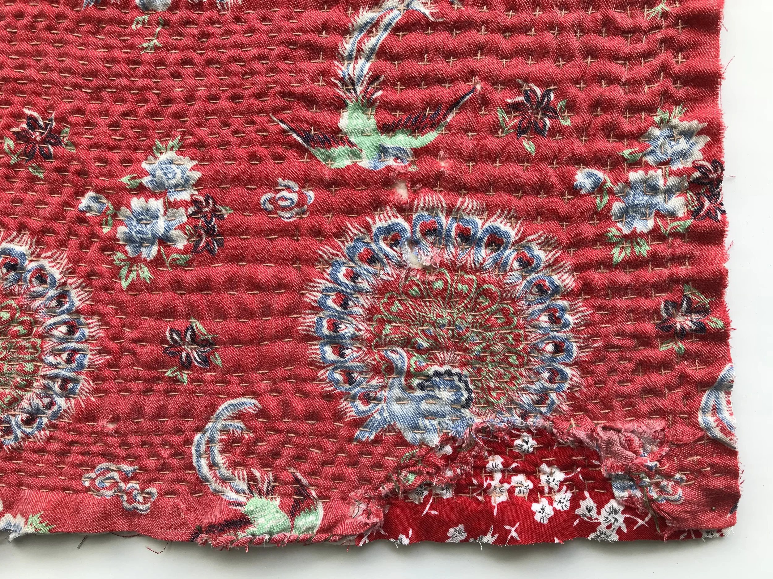 The bottom right corner of the quilt to focus on the patches of different fabrics being overlaid underneath the quilted fabric.