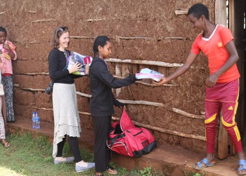 Saruma school boys pick up their hygiene packages from Cindy and her daughter.